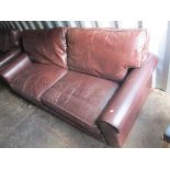 A large brown leather sofa with loose cushions