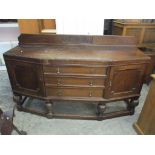 An early 20th century oak sideboard having a raised back, three drawers, two cupboard doors and on