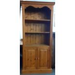 A modern pine bookcase having three shelves above two cupboard doors 183cm h x 81cm w x 32cm d