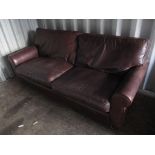 A large brown leather sofa with loose cushions