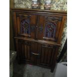 An early 20th century oak Gothic Revival cabinet having wrought iron supports, two painted