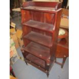 A pair of reproduction mahogany waterfall bookcases with base drawers, on turned legs and brass