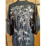 A Chinese black hand-sewn and hand-embroidered robe with images of embroidered flora and leaves in a