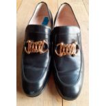 Gucci-A pair of Unisex Ice Lolly black leather loafers, having gold tone horse-bit style chain