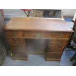 An Edwardian mahogany kneehole writing desk with inset brass handles, fielded cupboard door, one