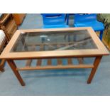 A vintage style coffee table with smoky glass top and slatted shelf below Location: A2