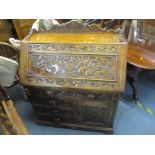 A Victorian carved oak bureau with a fall front, over a long drawer, three short drawers and a