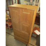 A modern pine wardrobe having two doors above three drawers on plinth base 177cm h x 90cm x 50cm d