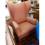 A Victorian wingback armchair in rose pink upholstery. Location:Back Row