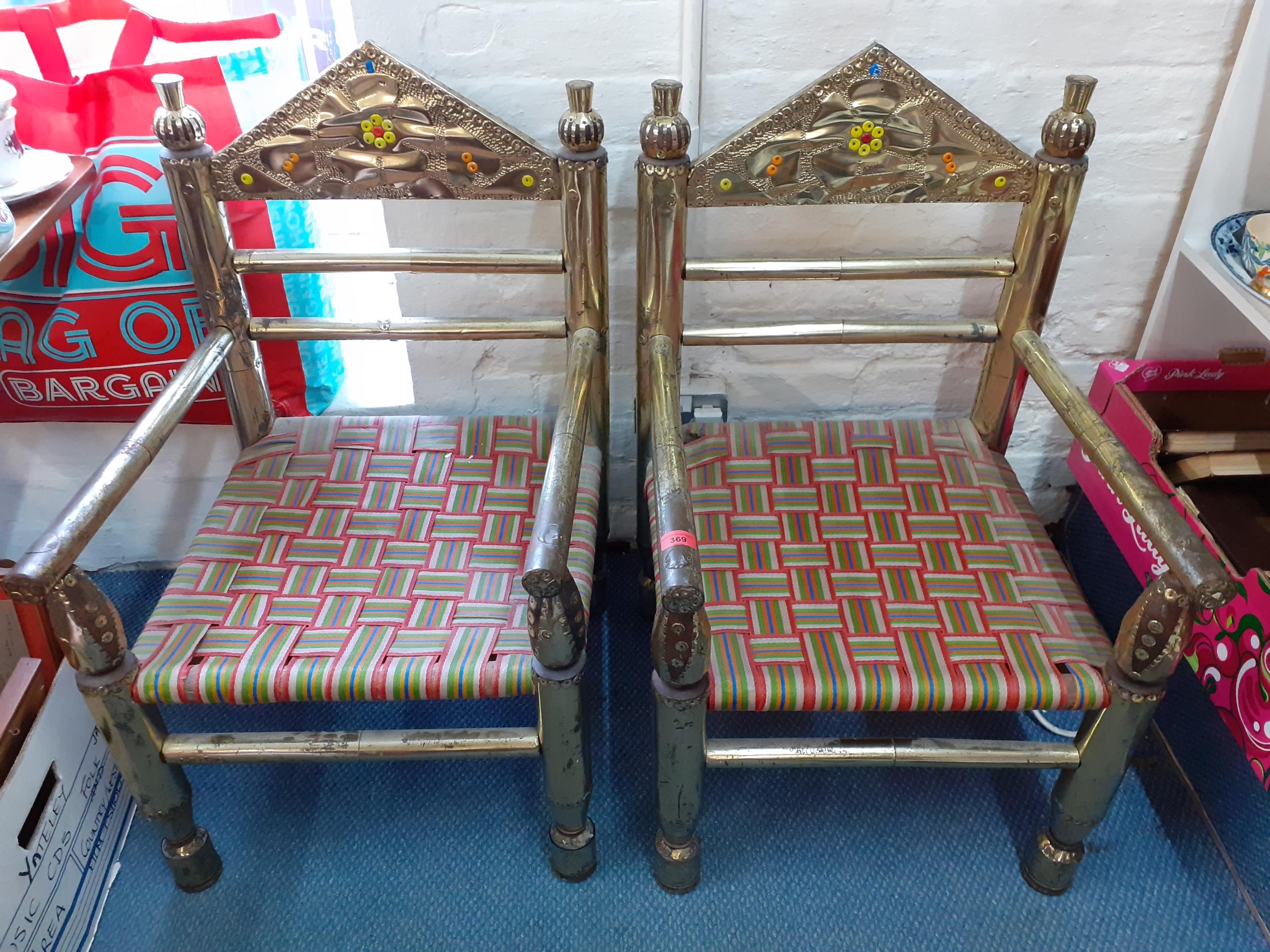 A pair of Middle Eastern inspired brass clad ornate open armchairs with strapwork seats