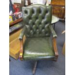 A 20th century mahogany leather button back upholstered swivel desk chair, upholstered in green