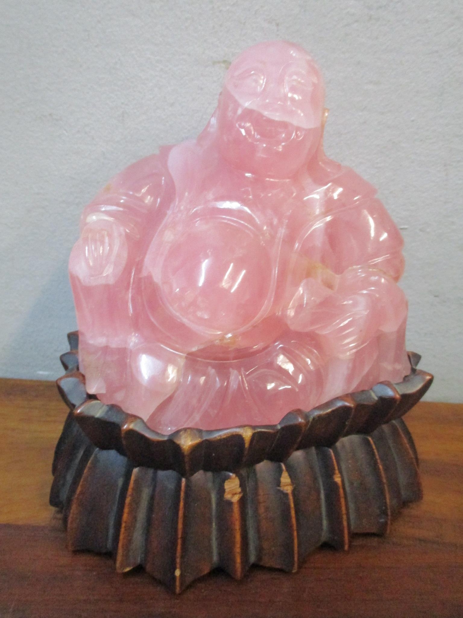 A carved pink stone model Buddha on a carved wooden base Location: