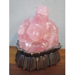 A carved pink stone model Buddha on a carved wooden base Location: