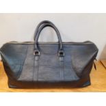 A modern black leather weekend bag with brushed gold tone hardware, 24" wide x 12" high