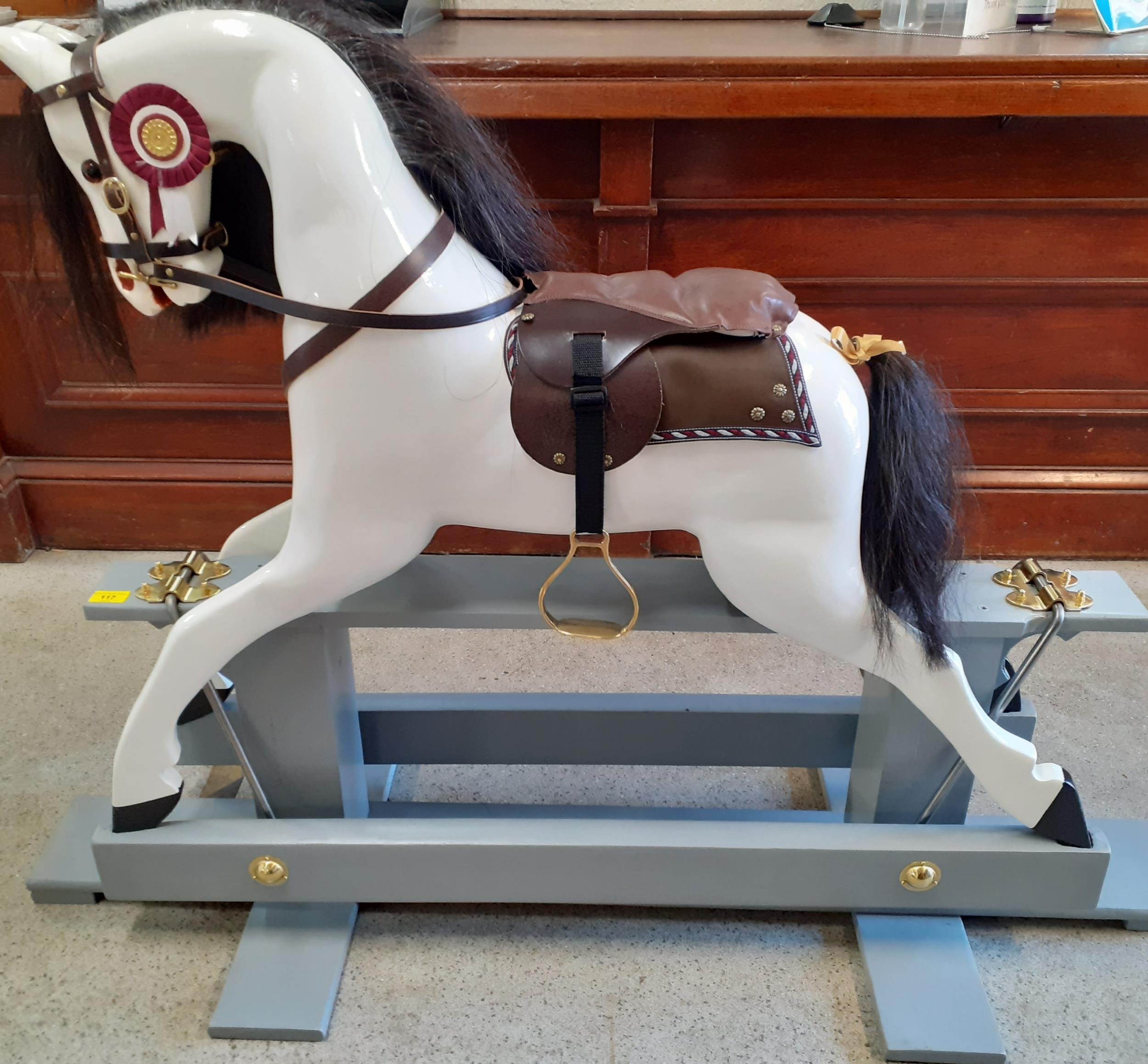A bespoke rocking horse in white on a grey painted stand with real black horse hair to the mane