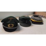 A group of three reproduction military caps to include a WWII German officers peaked cap, a WWII