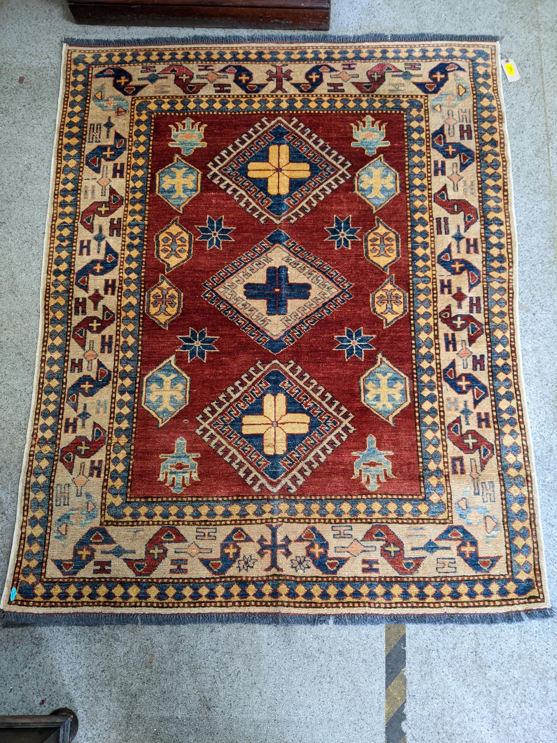 A Caucasian design Turkish rug with geometric motifs on a beige ground 160cm x 134cm