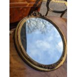 An early 20th century oval gilt mirror with floral and scrolled ornament