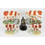 A pair of Victorian Staffordshire ceramic cows with calves, on natutalistic bases, together with a