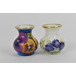 Two Moorcroft Enamels Ltd miniature vases, both of baluster form with painted pansies, the blue