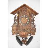 A late 19th/early 20th century Black Forest cuckoo clock, the heavily carved case in the form of a
