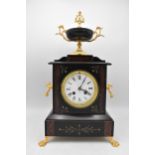 A late 19th century French marble mantle clock, having a twin gilt handled urn shaped finial, twin