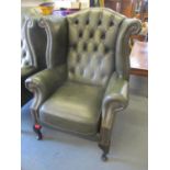 A reproduction green leather button wing back armchair Location: