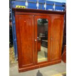 A Victorian mahogany wardrobe having a central mirrored door and two panelled doors, fitted with