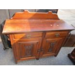 An early 20th century walnut cabinet having a raised back and two drawers above cupboard doors