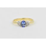 A 14ct yellow gold, diamond and tanzanite dress ring, with central oval cut tanzanite flanked with