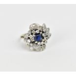 A white metal, diamond and sapphire dress ring, the central princess cut sapphire set in four claws,