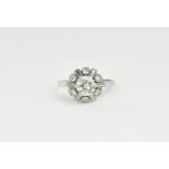 An Art Deco white metal and diamond cluster ring, with central brilliant cut diamond, roughly 0.70