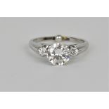 A 14ct white gold and brilliant diamond solitaire ring, the central stone roughly 1 carat, flanked