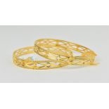 A pair of 22ct yellow gold wedding bangles, of circular form with pierced decorations and textured