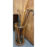 A reproduction circular stick/umbrella stand with mixed treen waling sticks, shoe horns and umbrella