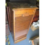 An early/mid 20th century oak tambour fronted filing cabinet having nine slide out shelves, 115cm