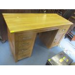 A modern light oak desk having five drawers and single cupboard door, 78cm h x 139.5cm w Location: