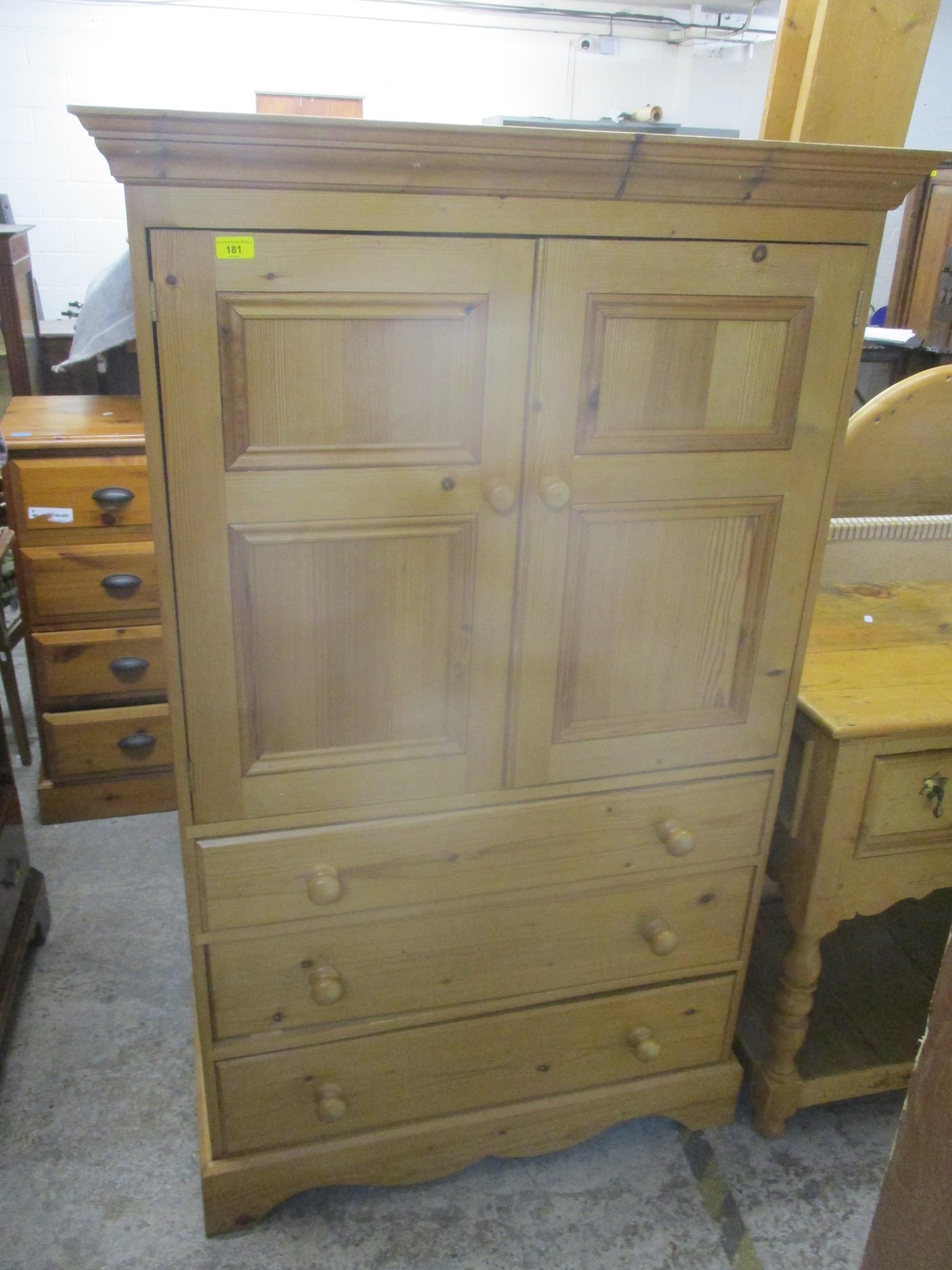 A contemporary pine side chest, twin cupboard door over three graduated drawers on bracket feet,