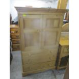 A contemporary pine side chest, twin cupboard door over three graduated drawers on bracket feet,