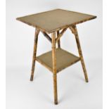 A late 19th century bamboo two tier occasional table, with hessian surfaces, on splayed legs, 64cm