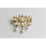 A gold coloured metal brooch set with three rows of pearls and three pearl pendants, stamped 14k,