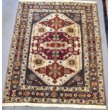 A Kazak rug with three medallions on an off white ground in red, blue, yellow, orange and brown,