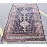 A Bokhara rug with twin diamond medallions and repeated flowers on a dark blue ground, 171cm x 282cm