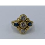 A yellow metal diamond and sapphire ring having three round brilliant cut diamonds approx 4.8mm