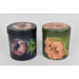 Two Moorcroft pottery lidded pots, to include a 'Hibiscus' pattern one with coral flower on green