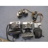 A group of vintage film and digital cameras and binoculars and monocles to include military stereo