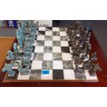 A chess set having a marble effect board and verdigris metal players in the Grecian style