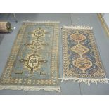 Two hand woven rugs both having blue grounds, geometric designs and tasselled ends Location: