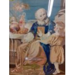 A 20th century tapestry in woollen cross-stitch depicting a religious man teaching a child, framed