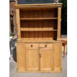 A large Victorian pine dresser having a plate rack above two drawers and cupboards below, 218.5cm